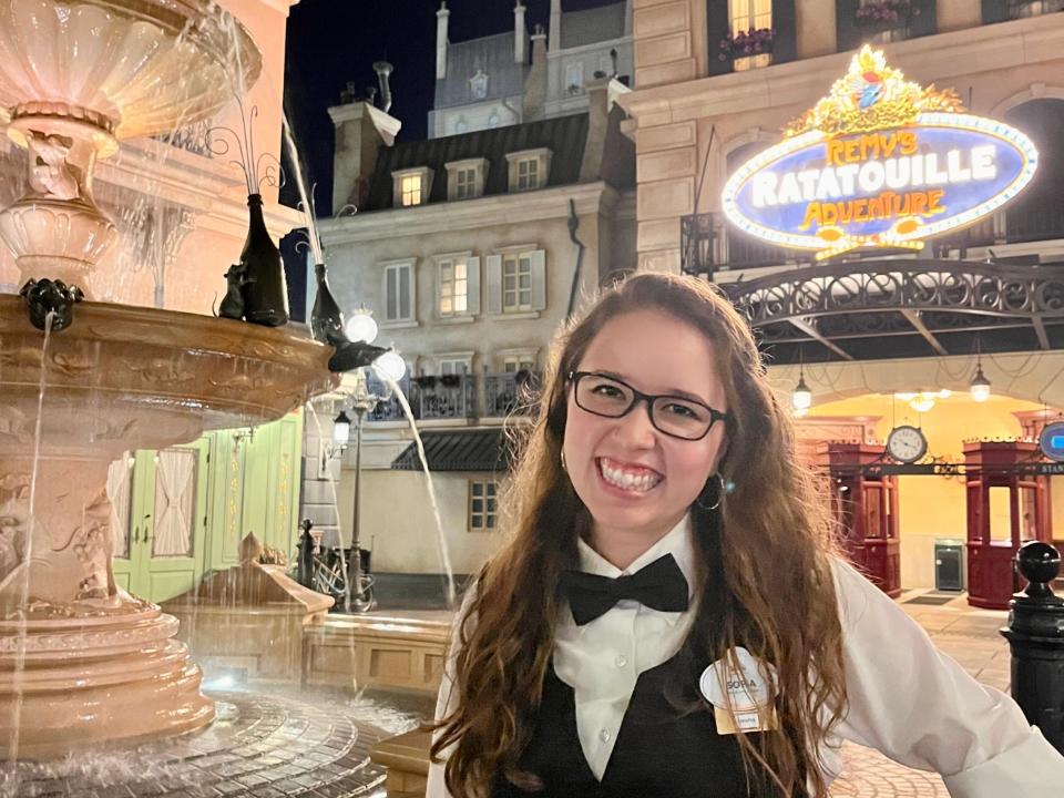 sofia posing for a photo in costume in the france pavilion at epcot in disney world