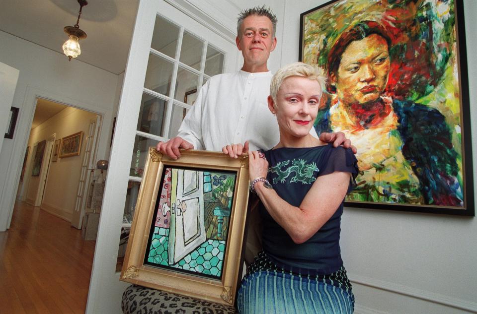 In this 2001 photo, Tom McCleery and Gunnel Humphreys display some of their collection of local art. They are holding a painting by Christian Pierre, while hanging behind them is a recent acquisition by Jonathan Lux.