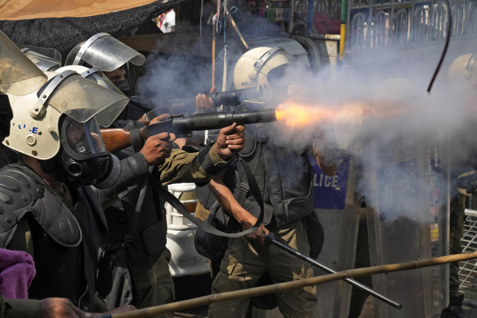 A riot police officer fires tear gas to disperse supporters of former Prime Minister Imran Khan during clashes, in Lahore, Pakistan, Wednesday, March 15, 2023. Supporters of Khan threw bricks at police who fought back with clubs and tear gas for a second day Wednesday after officers tried to arrest the ousted premier for failing to appear in court on graft charges.(AP Photo/K.M. Chaudary)