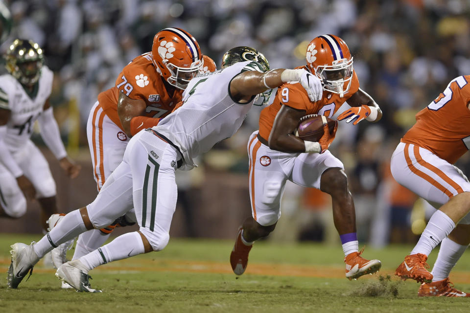 Clemson's Travis Etienne, right, rushes out of the tackle of Charlotte's Alex Highsmith, with blocking help from Jackson Carman (79) during the first half of an NCAA college football game Saturday, Sept. 21, 2019, in Clemson, S.C. (AP Photo/Richard Shiro)