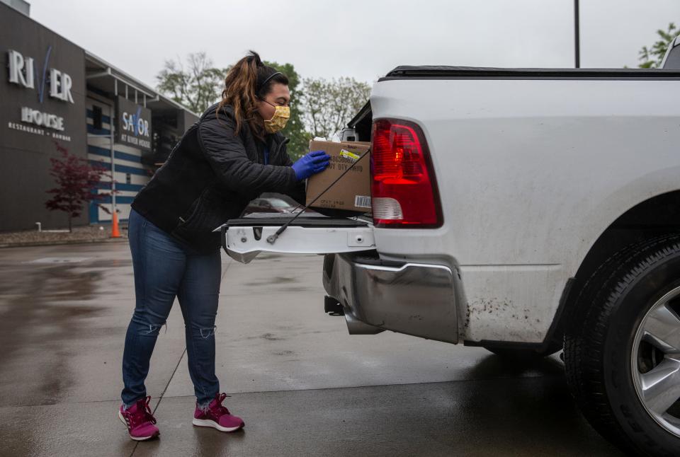 Riverhouse employees wear face masks as they place groceries inside customer's cars. The restaurant began selling groceries after the coronavirus pandemic shut down dining. Riverhouse employee Jennifer Vasquez places groceries in the bed of a pickup truck. May 13, 2020