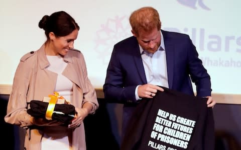 Prince Harry and Meghan, Duchess of Sussex react to gifts they received during a visit to Pillars - Credit: Reuters