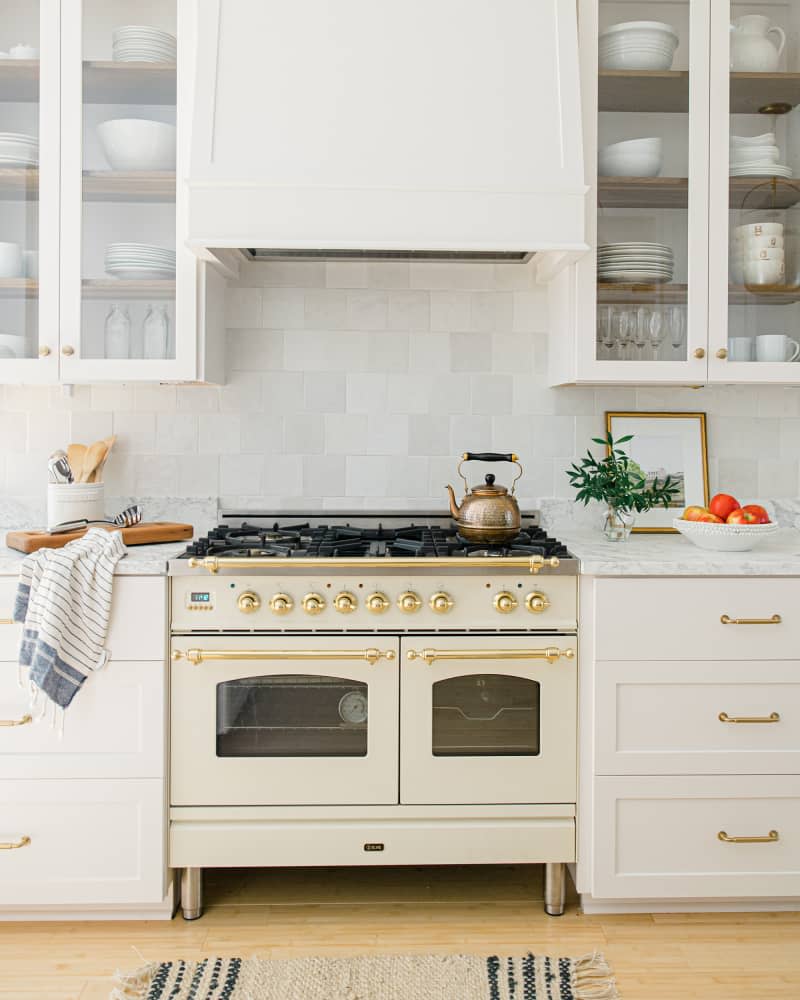 White kitchen with Italian stove, tile backsplash and brass accents