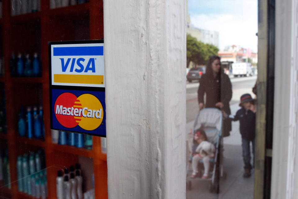 People walk by a window sticker advertising Visa and MasterCard credit cards. Photo: Justin Sullivan/Getty Images