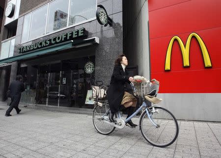 A cyclist rides past branches of Starbucks and McDonald's in the Jimbocho district of Tokyo, in this file picture taken March 15, 2007. REUTERS/Kevin Coombs/Files