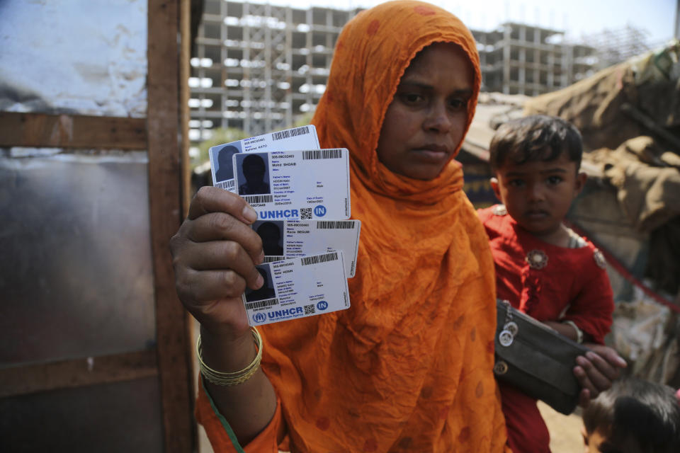 FILE - In this March 9, 2021 file photo, Rahima Kato, a Rohingya woman displays identity cards of her family members issued by United Nations High Commissioner for Refugees (UNHCR) at their makeshift camp on the outskirts of Jammu, India. Four Indian states bordering Myanmar have stepped up measures to prevent refugees from entering India through a porous border following last month's military coup in the Southeast Asian country, a government official said Saturday. (AP Photo/Channi Anand)