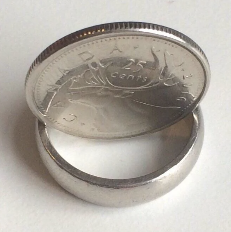 A Canadian quarter balancing on its edge above a ring on a surface