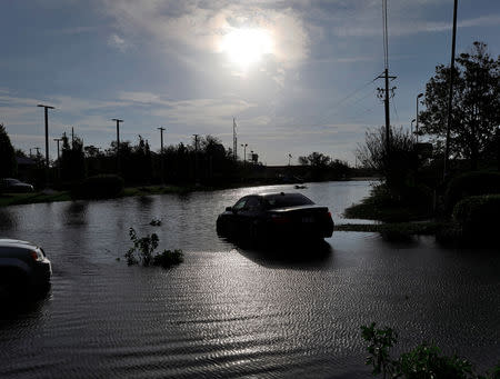 The sun reflects on flood water and stranded vehicles as it emerges after days of storm clouds and rain, in the aftermath of Hurricane Florence in Wilmington, North Carolina, U.S., September 17, 2018. REUTERS/Jonathan Drake