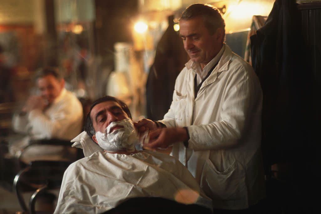 Barber shaving man's face