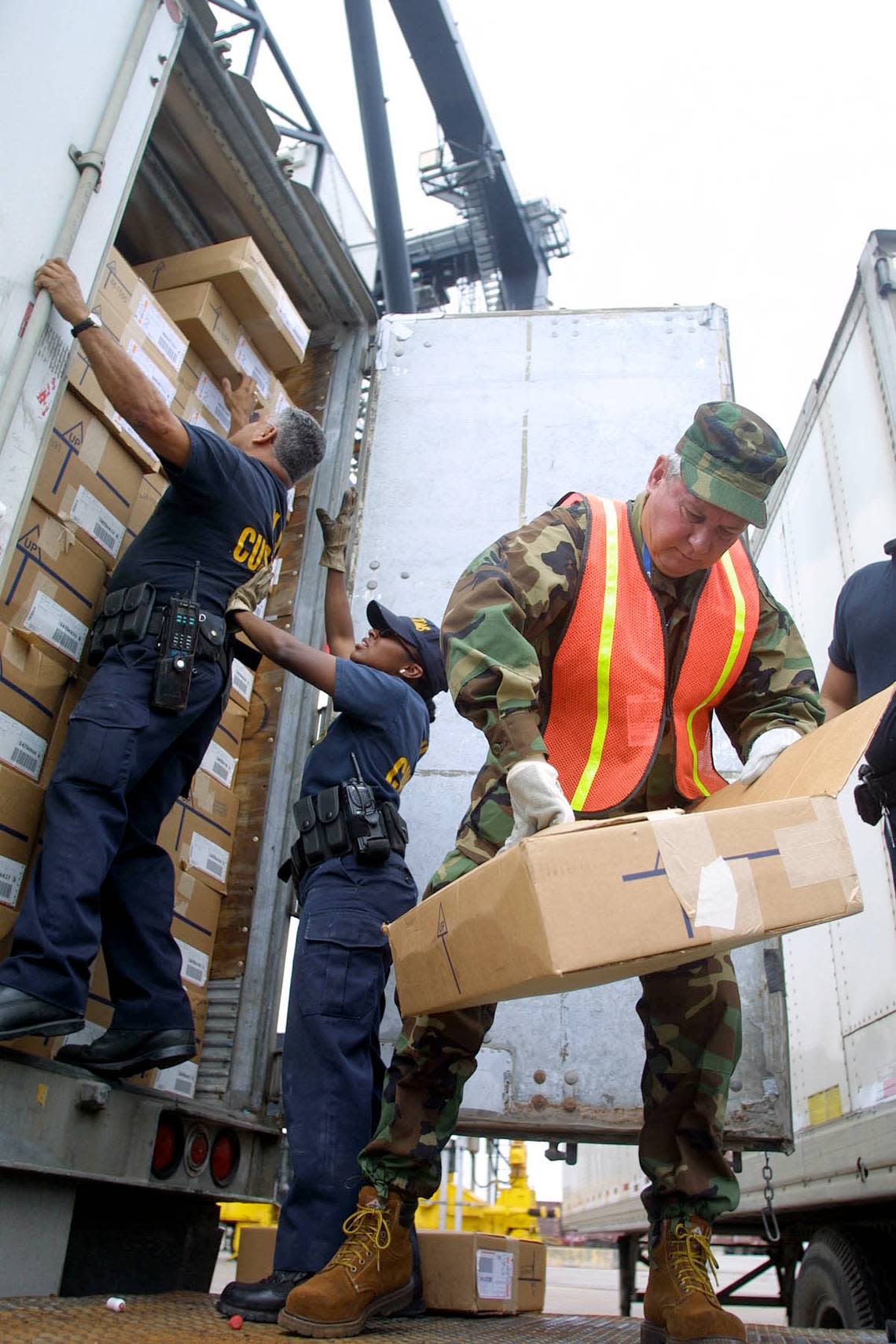 FOR BROWARD -- 01/03/02 -- SENATOR BOB GRAHAM WORK DAY AS PORT SECURITY -- MIAMI HERALD STAFF PHOTO BY CHUCK FADELY -- U.S. Senator Bob Graham, right, opens a box of jean shorts from Central America as he helps U.S. Customs inspectors go through a container at Port Everglades. Senator Bob Graham spent Thursday morning, January 3, 2002 working security for Port Everglades. He joined U.S. Customs agents in searching containers and then patrolled the waters of the port aboard the USCG Cutter Gannet. Chuck Fadely/Herald Staff