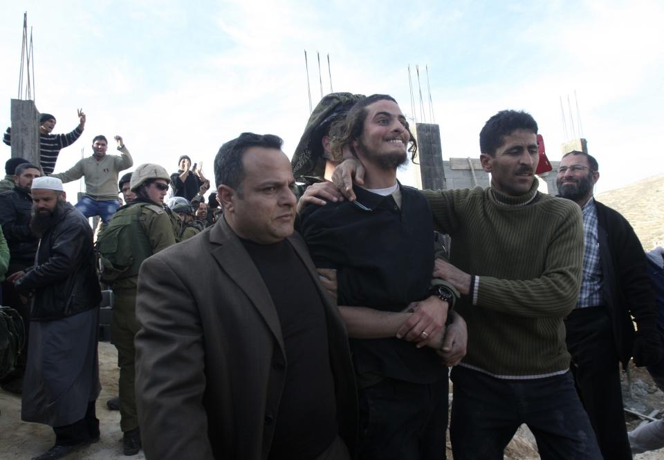 An Israeli soldier and a Palestinian villager escort away a Jewish settler after he was detained by Palestinian villagers near Nablus