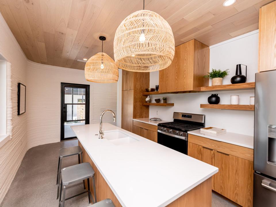 a kitchen island with contemporary lights next to a window