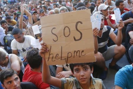 A child holds a self-made placard reading "SOS help me" outside the railways station in Budapest, Hungary September 2, 2015. REUTERS/Laszlo Balogh