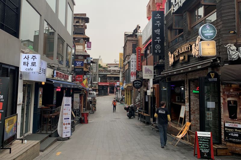 People wearing protective masks walk past on empty street in Itaewon following the coronavirus disease (COVID-19) outbreak in Seoul