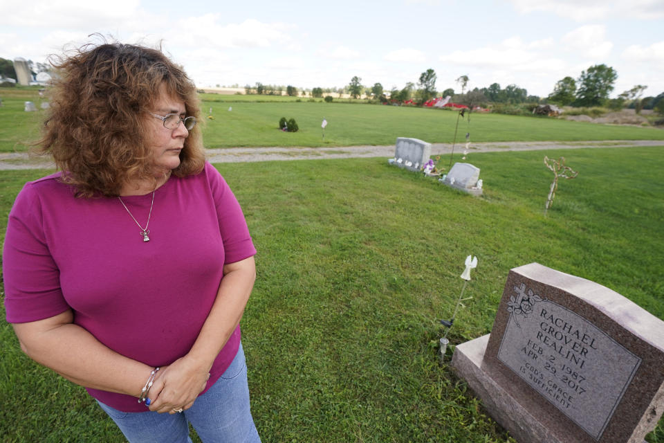 Sharon Grover looks down at the gravestone for her daughter, Rachael, Tuesday, Sept. 28, 2021, at Fairview Cemetery in Mesopotamia, Ohio. Grover believes her daughter started using prescription painkillers around 2013 but missed any signs of her addiction as her daughter, the oldest of five children, remained distanced. (AP Photo/Tony Dejak)