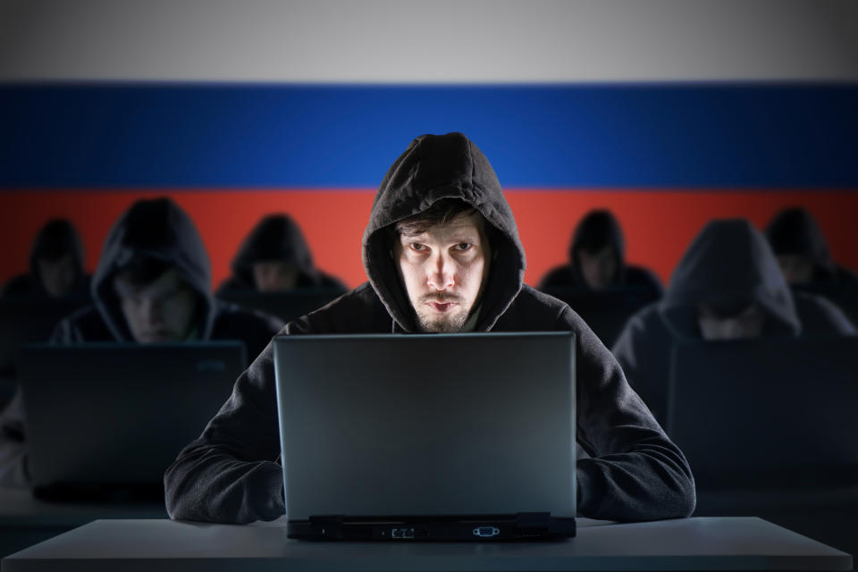 Muchos hackers rusos en la granja de trolls. Concepto de ciberdelincuencia y seguridad. Bandera de Rusia en el fondo. (Getty Creative)