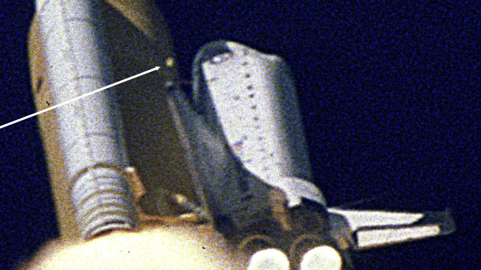 Ein Pfeil zeigt auf ein aus dem Außentank freigesetztes Stück Schaum, das dann auf die Vorderkante des linken Flügels des Space Shuttles Columbia trifft und das Schicksal der STS-107-Besatzung an Bord besiegelt.