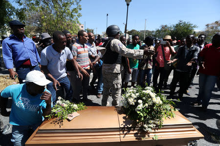 A riot policeman stands guard next to the casket of a man shot dead during anti-government protests in Port-au-Prince, Haiti, February 22, 2019. REUTERS/Ivan Alvarado