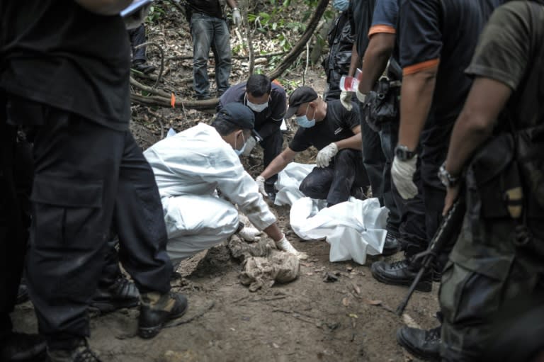 Malaysian police exhume dozens of graves found in a series of remote human-trafficking camps along the Thai border last year