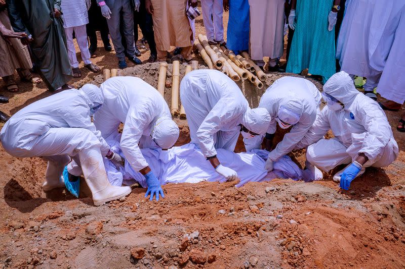 Men wearing protective gears carry the coffin of the Nigerian president's chief of staff Abba Kyari