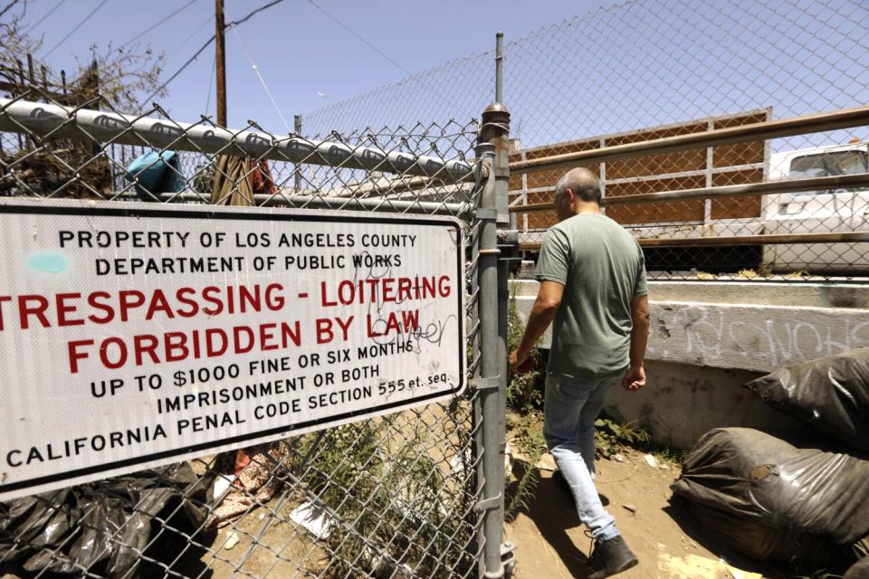 Gustavo Flores walks past a sign that states trespassing and loitering is forbidden by law on city property in Watts.