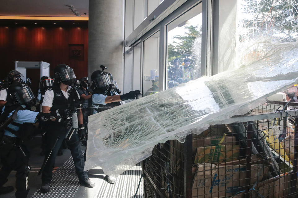 Police officers spray pepper spray as protesters use a cart to ram into the glass wall of the Legislative Council in Hong Kong on Monday, July 1, 2019. The embattled leader of Hong Kong pledged Monday to be more responsive to public sentiment, as police faced off with protesters on the 22nd anniversary of the former British colony's return to China. (Steve Leung/HK01 via AP)