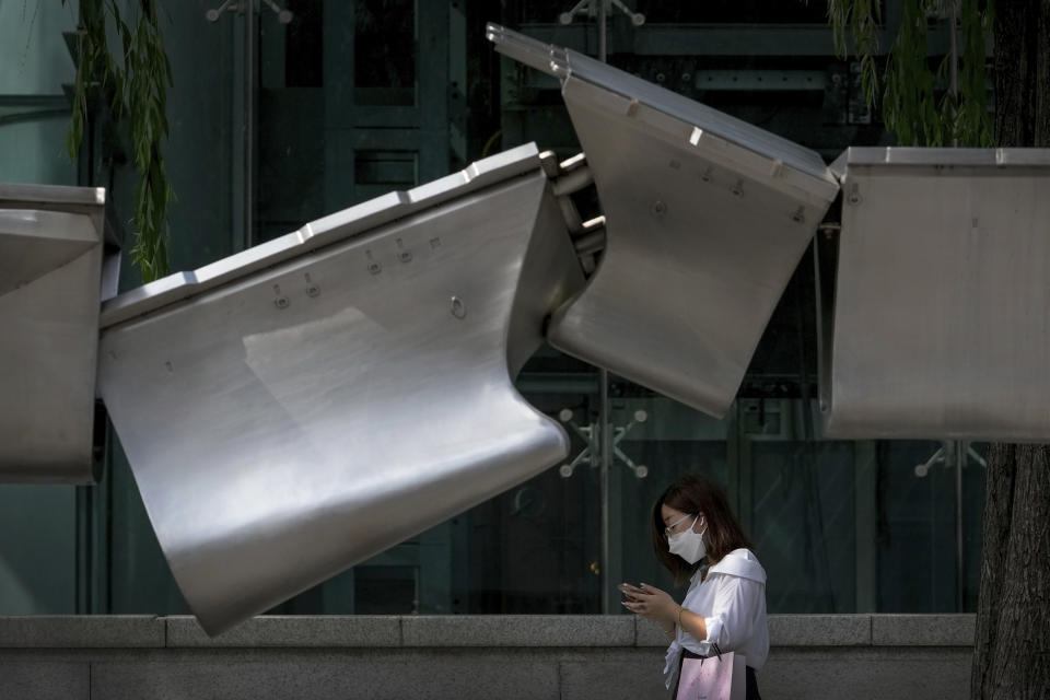 A woman wearing a face mask walks by an art installation depicting two colliding aircraft carriers on display outside a mall in Beijing, Sunday, Aug. 7, 2022. Taiwan said Saturday that China's military drills appear to simulate an attack on the self-ruled island, after multiple Chinese warships and aircraft crossed the median line of the Taiwan Strait following U.S. House Speaker Nancy Pelosi's visit to Taipei that infuriated Beijing. (AP Photo/Andy Wong)