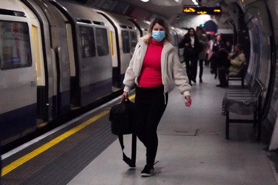 A woman wearing a protective mask walks along the platform at Leicester Square underground station in London (Reuters)