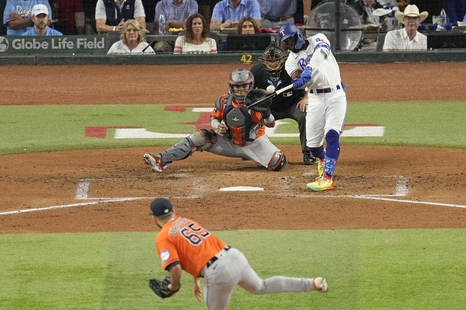 Texas Rangers' Adolis Garcia, right, hits a home run off Houston Astros starting pitcher Jose Urquidy (65) as catcher Martin Maldonado reaches for the pitch during the second inning in Game 4 of the baseball American League Championship Series Thursday, Oct. 19, 2023, in Arlington, Texas. (AP Photo/Tony Gutierrez)
