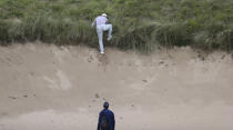 Gary Woodland of the United States attempts to find a sure footing to play his ball that is on the top edge of a bunker on the 7th hole during the first round of the British Open Golf Championships at Royal Portrush in Northern Ireland, Thursday, July 18, 2019.(AP Photo/Peter Morrison)
