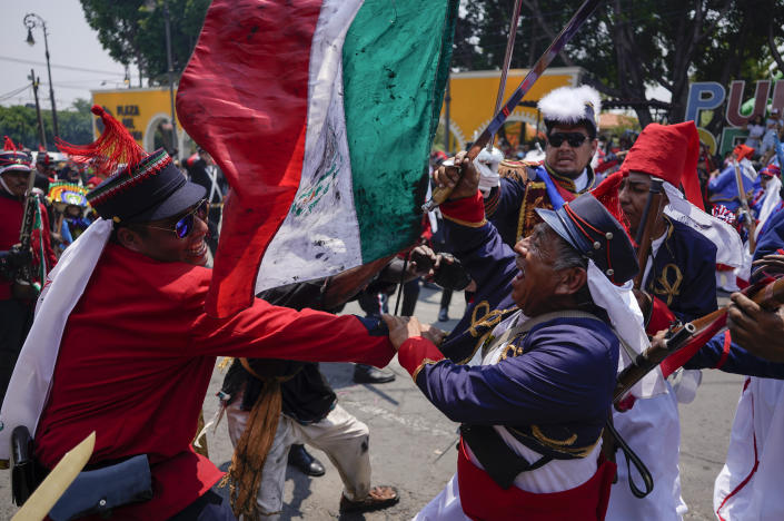 People dressed as Zacapoaxtla Indigenous people clash with others playing the part of French soldiers as they reenact The Battle of Puebla as part of Cinco de Mayo celebrations in the Peñon de los Baños neighborhood of Mexico City, Thursday, May 5, 2022. Cinco de Mayo commemorates the victory of an ill-equipped Mexican army over French troops in Puebla on May 5, 1862. (AP Photo/Eduardo Verdugo)