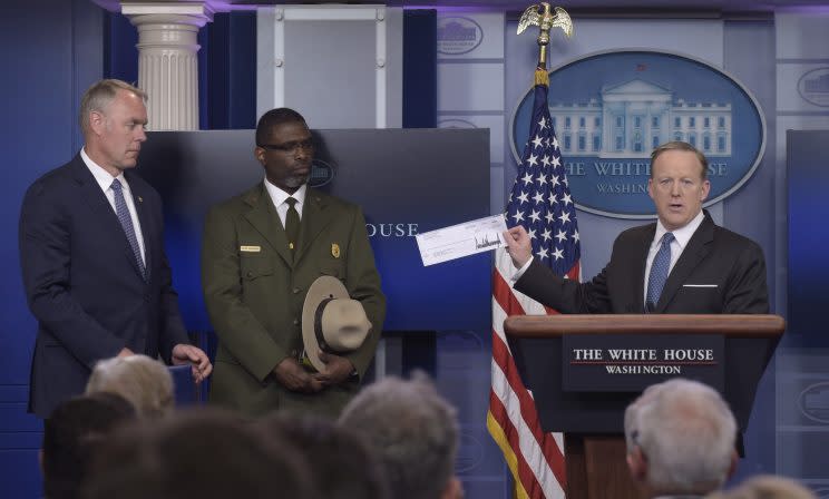 Sean Spicer überreicht Innenminister Ryan Zinke (l.) und dem Leiter des Harpers Ferry National Historic Park, Tyrone Brandyburg (m.), den Scheck mit Trumps Spende (Bild: AP Photo/Susan Walsh)