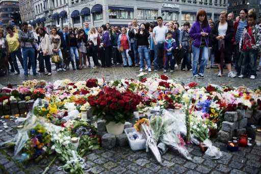 People stand by flowers and candles as they gather on July 23, 2011 in Oslo to mourn and show their respect for the victims of the twin attacks the day before. Anders Behring Breivik, who is set to go on trial on April 16 for killing 77 people in the attacks, said in a letter published Wednesday that being sentenced to psychiatric care would be the worst fate imaginable