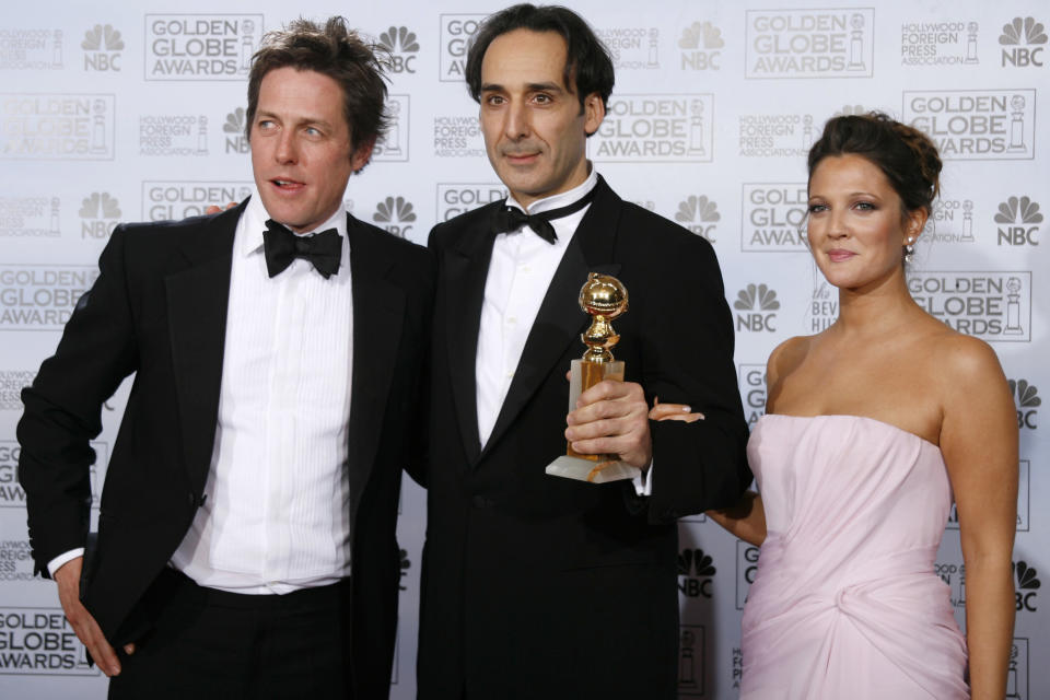 Alexandre Desplat (C) poses with his award for best original score - motion picture for "The Painted Veil" as he stands with presenters Hugh Grant and Drew Barrymore at the 64th annual Golden Globe Awards in Beverly Hills, California January 15, 2007.     REUTERS/Mike Blake (UNITED STATES)