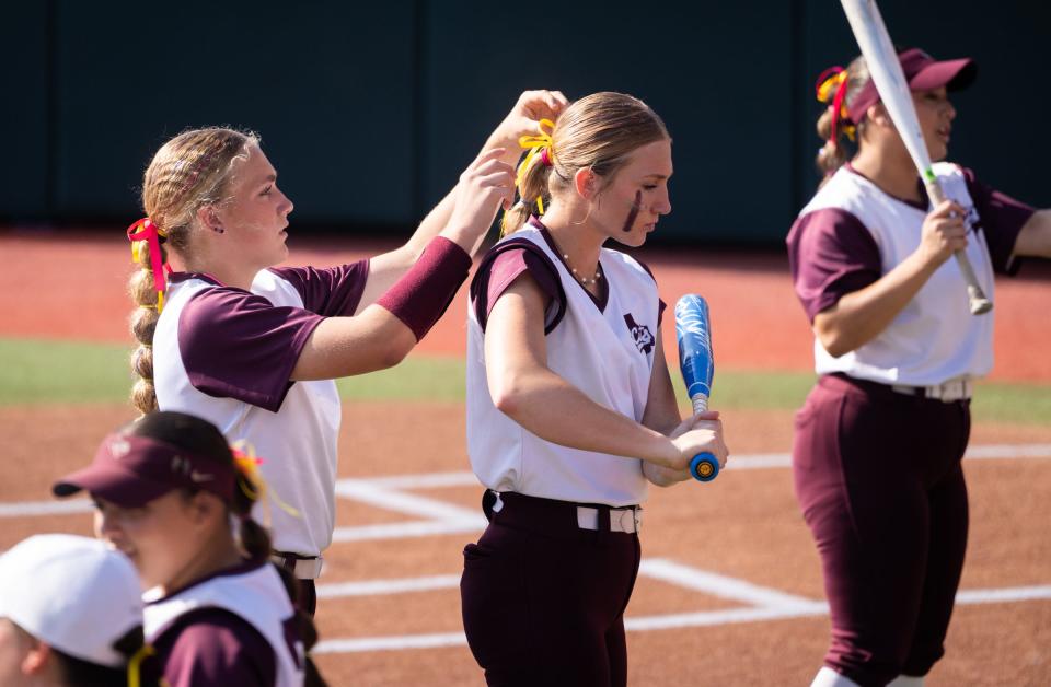 Calallen High School softball first baseman Braelyn Bailey, left, helps pitcher Jordyn Thibodeaux with a hair adjustment as the team warms up ahead of their 9-7 win over Liberty High School in the State 4A UIL Championships at Red and Charline McCombs Field in Austin, June 3, 2023.