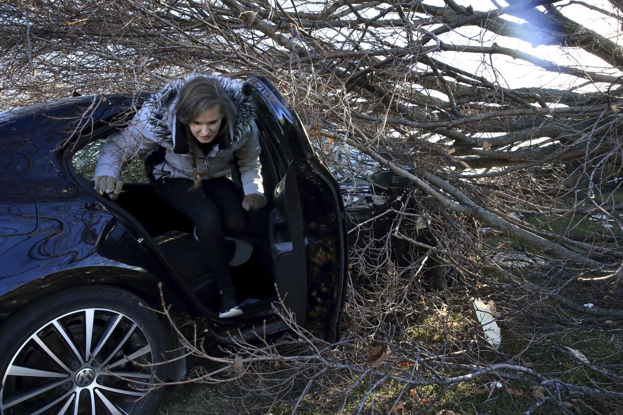 Hannah Binder climbs out her car on Monday, Dec. 13, 2021, after gathering some personal items from inside it because her insurance company totaled the car that was hit by a tree during Friday's tornado at her family's home and business, Brockmeier Sod Farm, in Edwardsville, Ill. The tornado damaged buildings, vehicles and trees on the property. (David Carson/St. Louis Post-Dispatch via AP)