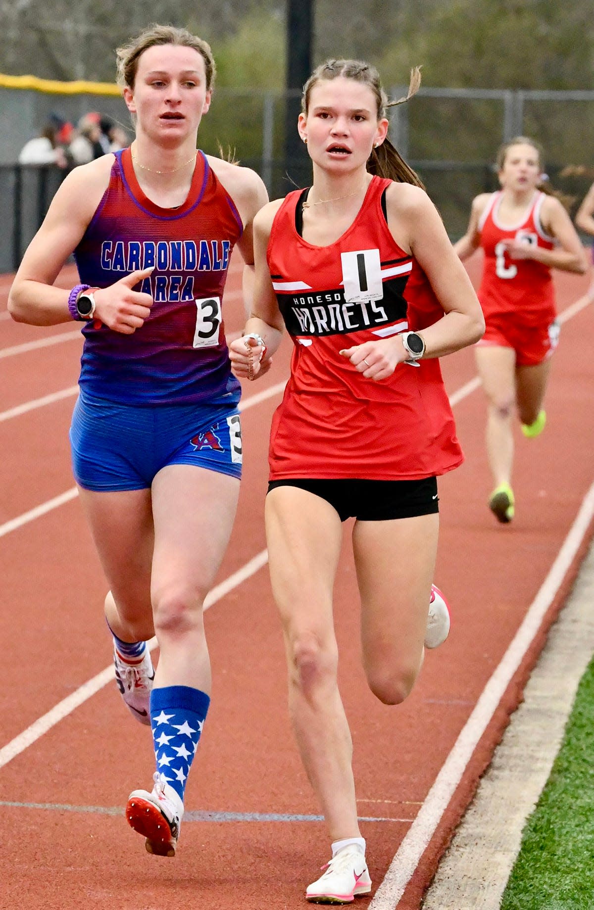 Honesdale's Brenna Dahlgren powers into the lead in the 1600M during Lackawanna League track & field action versus Carbondale Area.