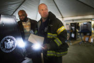 Rockaway resident and New York City firefighter Terence O'Donnell holds a flashlight while voting in a makeshift tent set up as a polling place at Scholars' Academy, PS 180, in the Rockaway neighborhood on November 6, 2012 in the Queens borough of New York City. The Rockaway section of Queens was one of the hardest hit areas and O'Donnell's home is damaged. Many voters in New York and New Jersey are voting at alternate locations in the presidential election due to disruption from Superstorm Sandy. (Photo by Mario Tama/Getty Images)