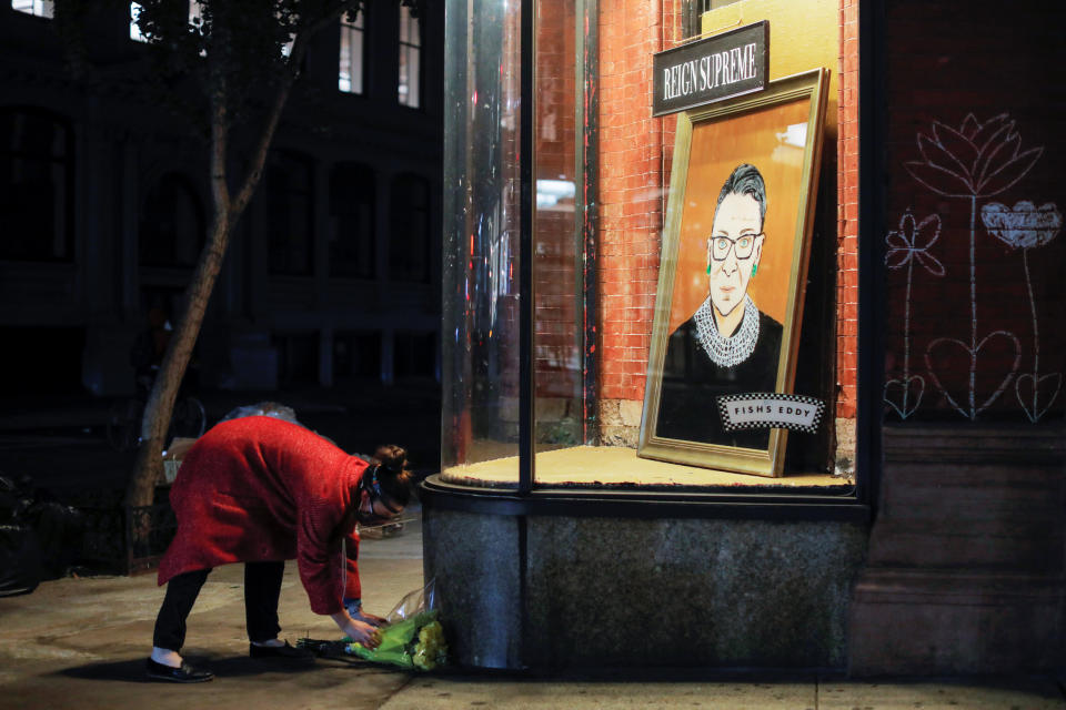 Image: A person places flowers in front of a painting in a storefront on Broadway of Associate Justice of the Supreme Court of the United States Ruth Bader Ginsburg who passed away in Manhattan, New York City (Andrew Kelly / Reuters)