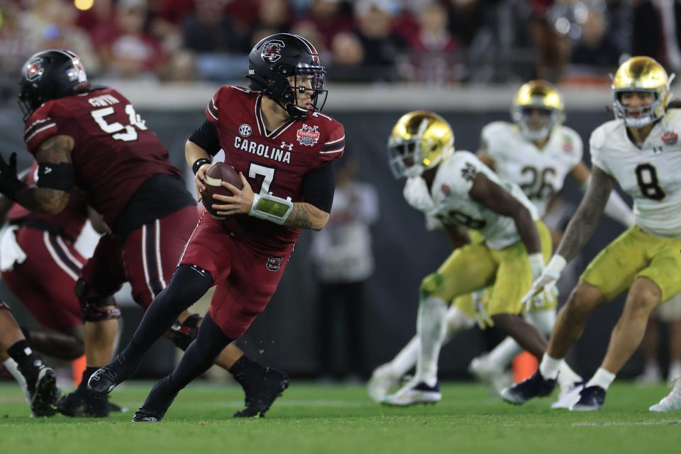 South Carolina quarterback Spencer Rattler rolls out during the third quarter of the 2022 TaxSlayer Gator Bowl at TIAA Bank Field.