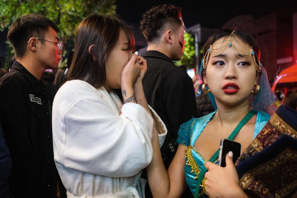 Two women wearing costumes look distraught.