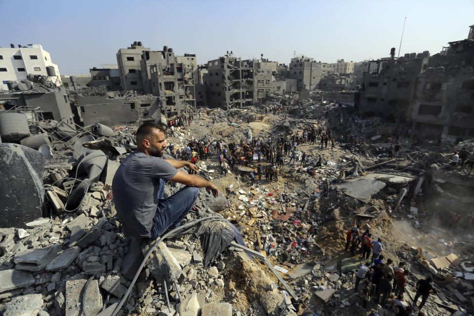 A man sits on the rubble as others wander among debris of buildings that were targeted by Israeli airstrikes in Jabaliya refugee camp, northern Gaza Strip, Wednesday, Nov. 1, 2023. (AP Photo/Abed Khaled)