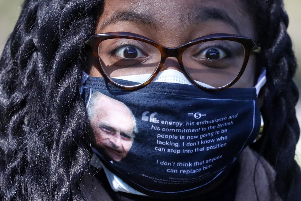 A woman wears a face covering with a picture of the Duke of Edinburgh as he walks along the Long Walk in Windsor, Saturday, April 17, 2021. Britain's Prince Philip, husband of Queen Elizabeth II, died Friday April 9, aged 99, his funeral service takes place at Windsor Castle in St George's Chapel. (AP Photo/Frank Augstein)