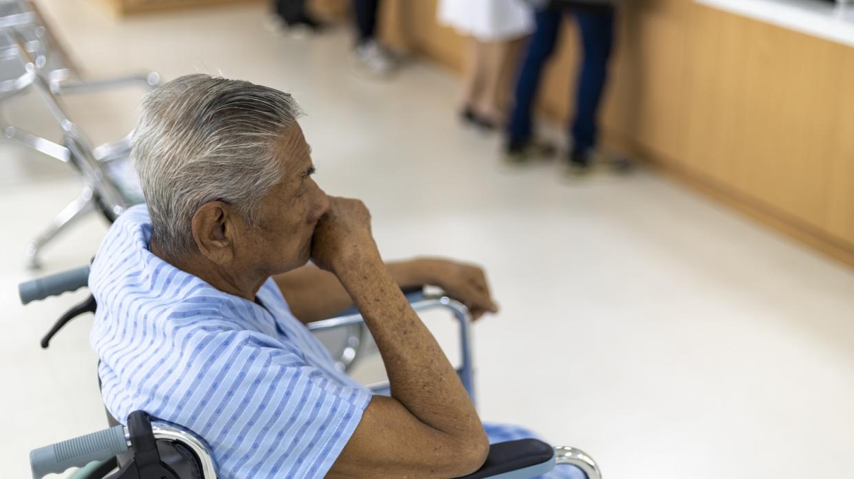 An old asian man sitting in a wheelchair at a clinic.