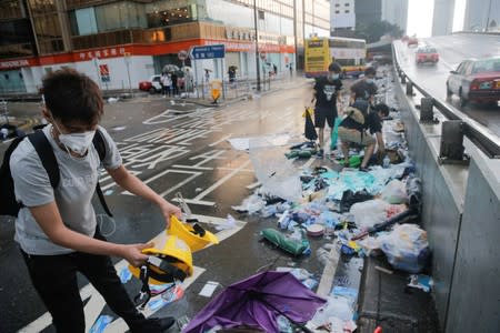 People pick out helmets, umbrellas and other items from rubbish left behind after violent clashes during a protest against a proposed extradition bill with China in Hong Kong