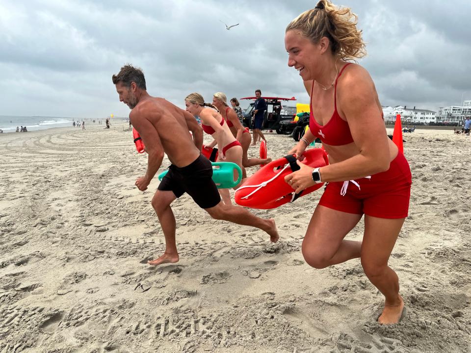 Hampton Beach lifeguards rush into the water during one of several demonstrations at Thursday's Water Safety Day.