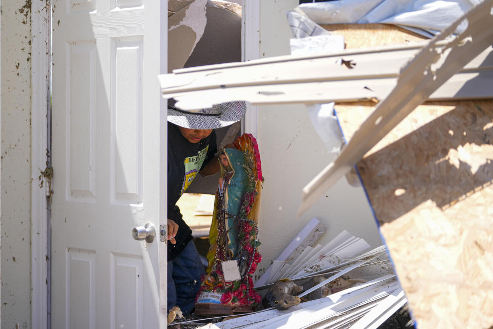 Larry Landeros, 9, who rode out a deadly tornado with his parents in their pick-up parked in their garage, salvages a Guadalupe Virgin statue while combing through debris of his home, Sunday, May 26, 2024, in Valley View, Texas. Powerful storms left a wide trail of destruction Sunday across Texas, Oklahoma and Arkansas after obliterating homes and destroying a truck stop where drivers took shelter during the latest deadly weather to strike the central U.S. (AP Photo/Julio Cortez)