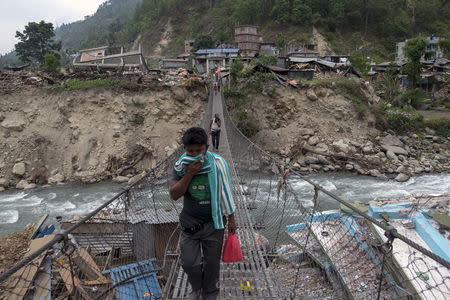 Local residents walk on a bridge, past collapsed buildings, after Tuesday's earthquake at Singati Village, in Dolakha, Nepal, May 15, 2015. REUTERS/Athit Perawongmetha