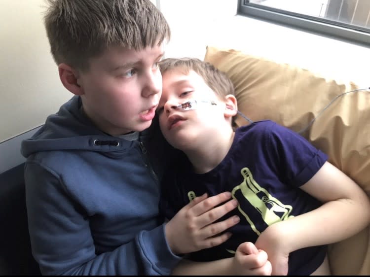 A young boy cradling his ill younger brother