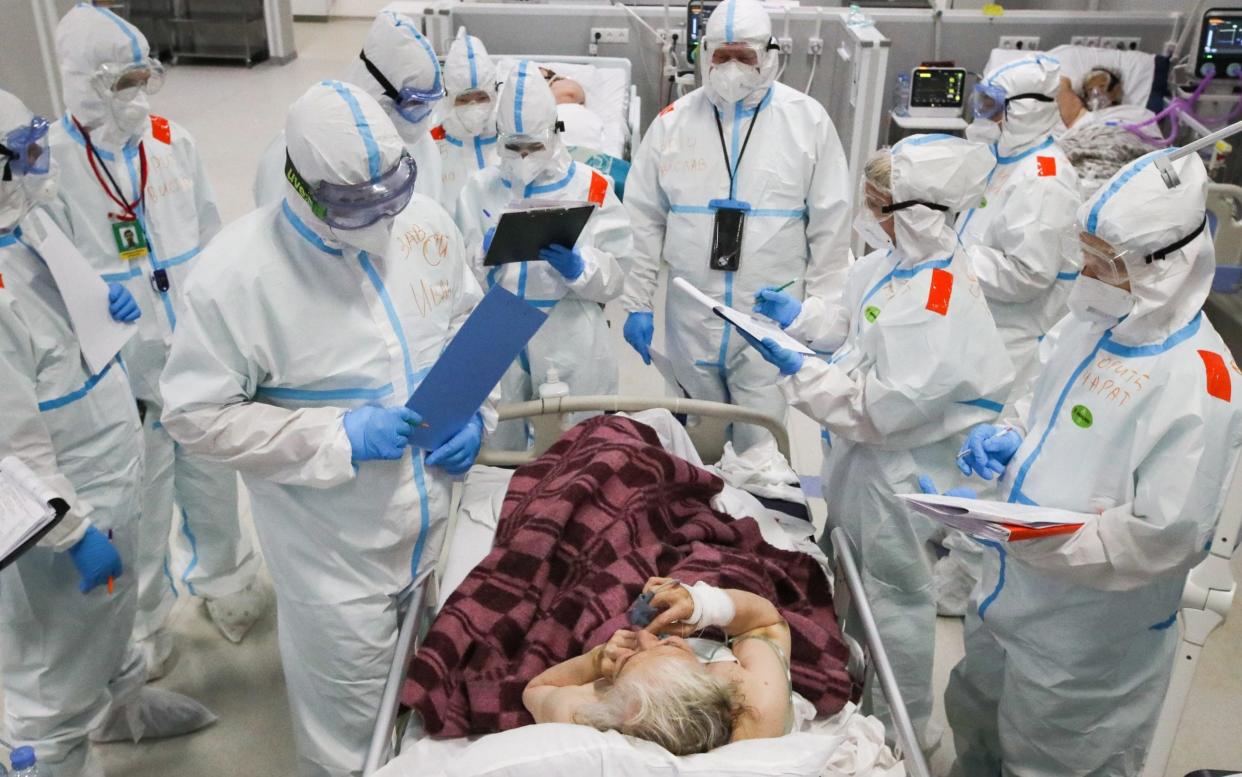 Medical workers in protective gear talk to a patient in a COVID-19 field hospital in the Sokolniki Exhibition and Convention Centre - Sergei Karpukhin